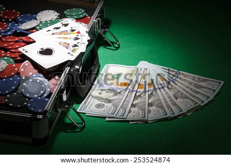 Poker chips and dollar bills in case on green background