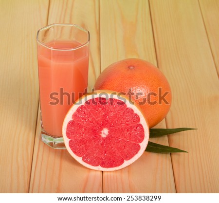 Glass of juice and grapefruit on wooden background