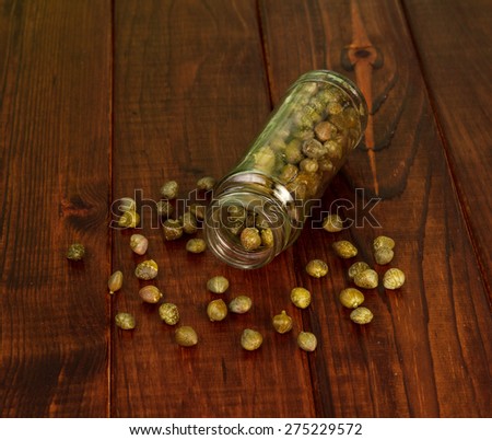 Capers in glass jar on rustic wooden table