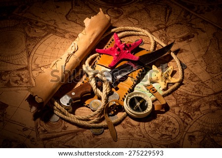 Old compass lying on antique map with rope, knife, money,globe and starfishes
