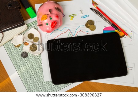 Business report. Above view of piggy bank and tablet over documents