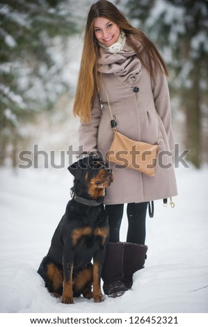 Young woman with her dog in the winter forest