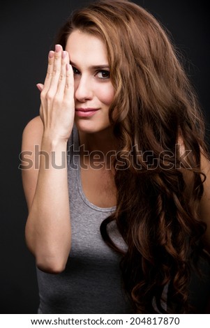 portrait of a girl in a gray T-shirt with a hand on the face. on a gray background