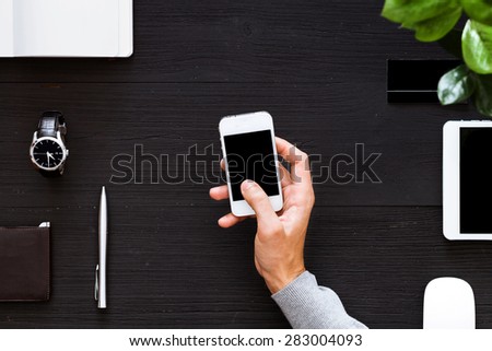 Working with the phone on a black background, overhead view. Man works with the phone that will quickly carry out the work. A touch of the finger on the screen.