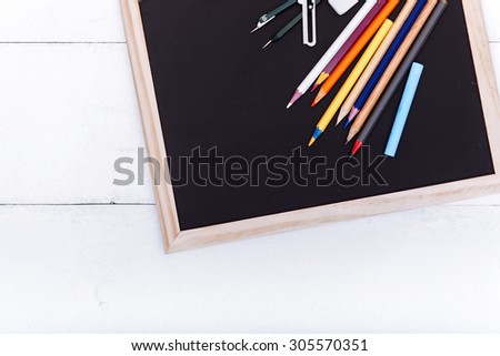 White, wooden table top view of the artist. On the table laid out creative stationery items to draw, paint, chalk board, stickers. For convenient and fast work of the artist.
