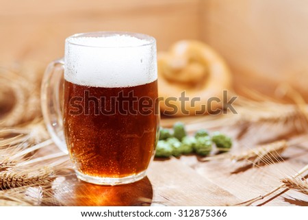 Original bavarian Oktoberfest background.  Glass of beer on wooden background with hops, wheat and Pretzel. Mug of beer festival template background.