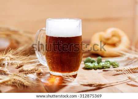 Original bavarian Oktoberfest background.  Glass of beer on wooden background with hops, wheat and Pretzel. Mug of beer festival template background.