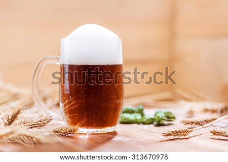 Oktoberfest background. Glass of beer on wooden background with hops, wheat and Pretzel. Mug of beer festival template background.