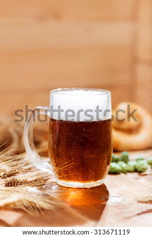 Oktoberfest background. Glass of beer on wooden background with hops, wheat and Pretzel. Mug of beer festival template background.