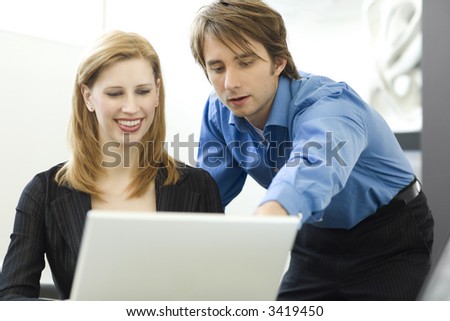 Workers talk while using a laptop computer