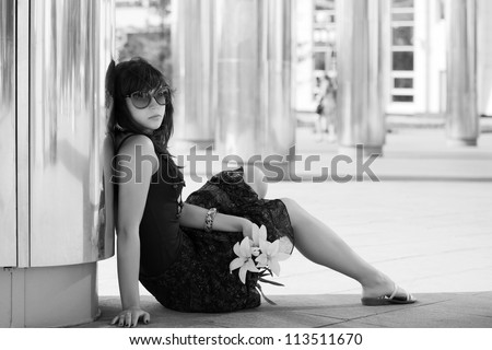 Sad young woman sitting on a sidewalk
