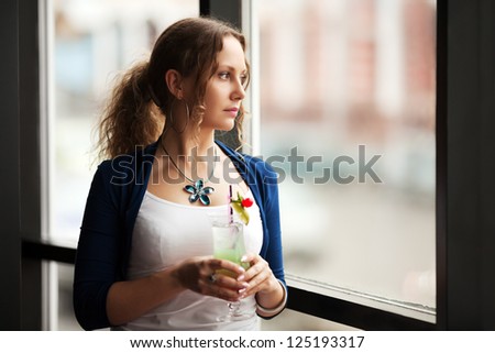 Sad woman with cocktail looking out the window