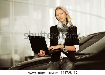 Young business woman with laptop against office windows
