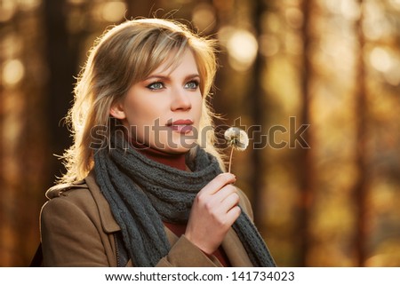 Blond woman with dandelion in autumn forest