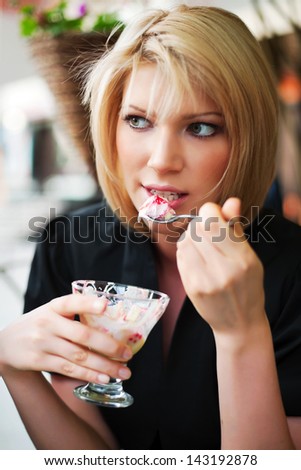Blond woman eating an ice cream at sidewalk cafe