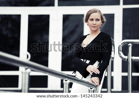 Sad beautiful woman in black leaning on the handrail
