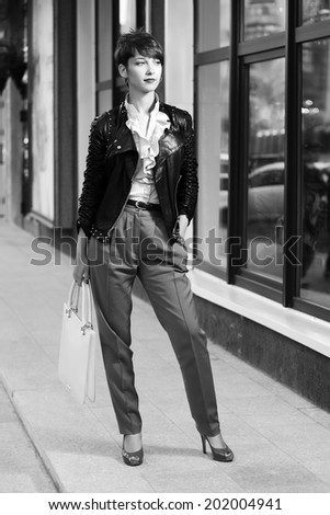 Young fashion woman in leather jacket at the mall window