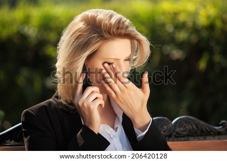 Sad business woman calling on the cell phone in a city park