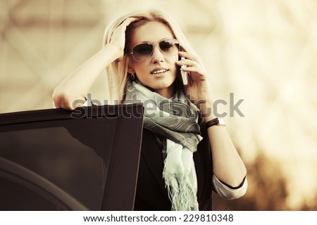 Fashion business woman calling on mobile phone at the car