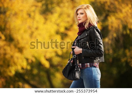 Young fashion blond woman in leather jacket in autumn park