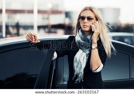 Fashion business woman calling on the phone by her car
