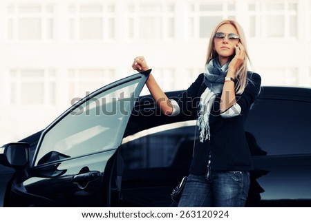 Fashion business woman calling on the phone by her car