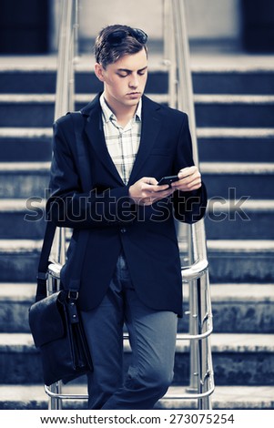 Young fashion business man looking at mobile phone