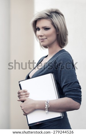 Happy young business woman with notebook at office building