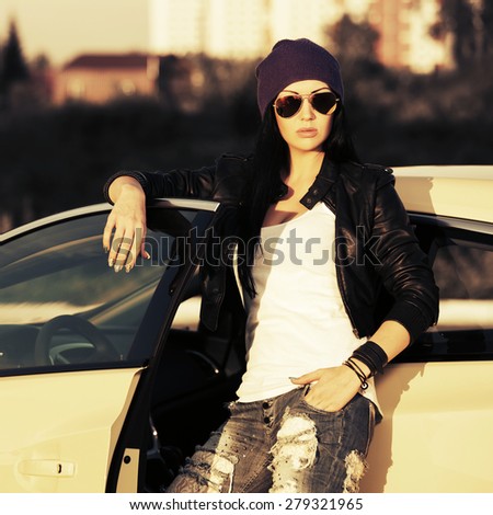 Young fashion punk woman by her car