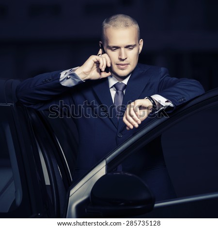 Young businessman calling on the phone by his car