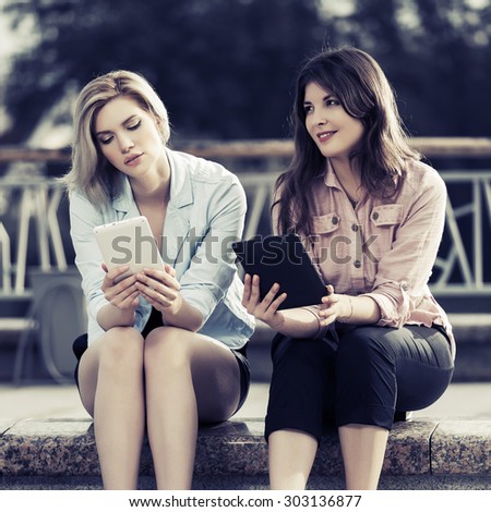 Two young fashion women with a digital tablet computers