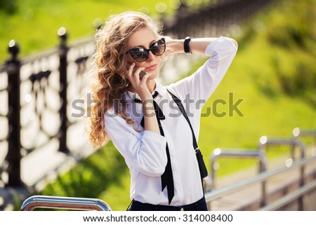 Fashion business woman in sunglasses calling on mobile phone