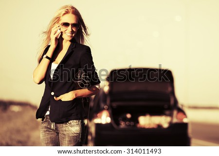 Fashion woman next to broken car calling on cell phone
