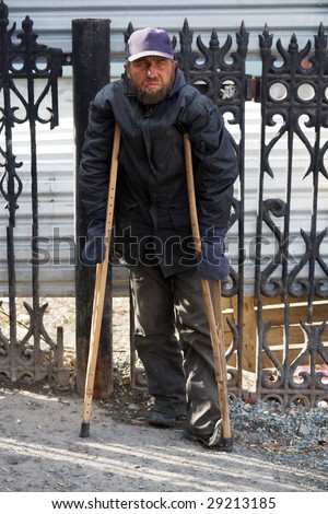 Disabled homeless man walking on crutches.