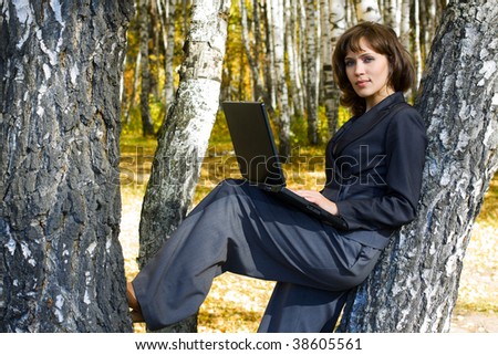 Young businesswoman using laptop in the birch forest.