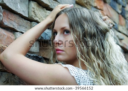 Beautiful sad lady against a stone wall.