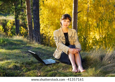 Young businesswoman using laptop in the forest.