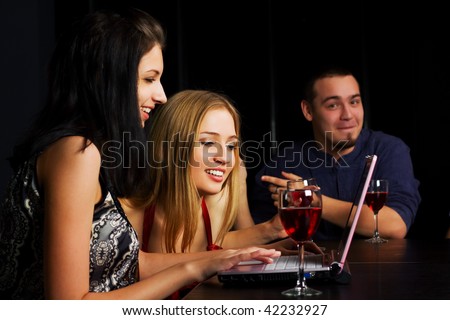 Young friends working on laptop in a night bar.