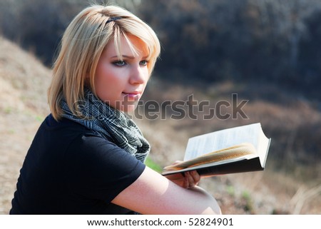 Young woman reading a book on nature.