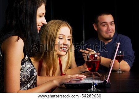 Young friends with laptop in a night bar.