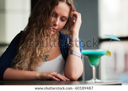 Sad young woman with cocktail at a restaurant.