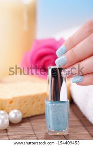 Manicure - Beautifully manicured woman\'s fingernails with glitter blue nail polish and nail art on fourth finger. Studio shot. Selective focus.