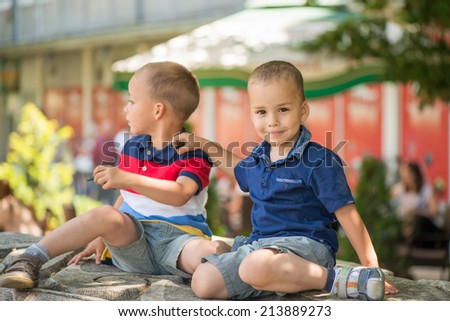 Twin brothers enjoy  outdoor in a park. Focus on child with blue t-shirt..