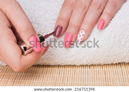 Manicure - Beauty treatment photo of nice manicured woman fingernails. Feminine nail art with nice glitter, pink and white nail polish.