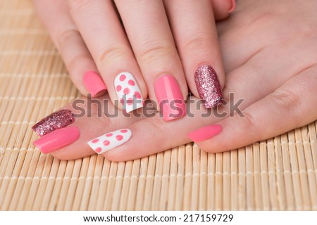 Manicure - Beauty treatment photo of nice manicured woman fingernails. Feminine nail art with nice glitter, pink and white nail polish. Selective focus.
