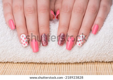 Manicure - Beauty treatment photo of nice manicured woman fingernails. Feminine nail art with nice glitter, pink and white nail polish.