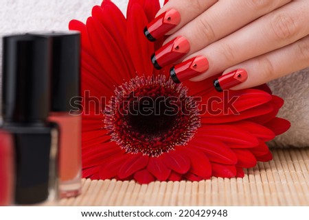 Manicure - Beautifully manicured woman fingernails with interesting feminine nail design touching flower.