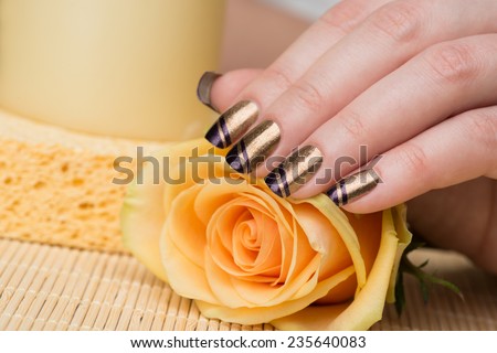 Manicure - Beauty treatment photo of nice manicured woman fingernails. Very nice holiday nail art with nice gold and purple nail polish. Selective focus.