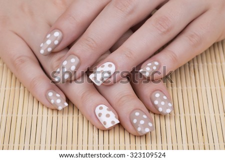 Manicure - Beauty treatment photo of nice manicured woman fingernails. Very nice feminine nail art with nice nude and white nail polish. Selective focus.