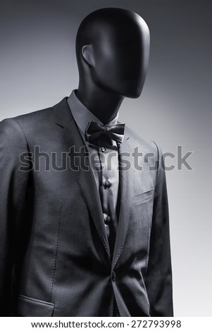 Fashion mannequin in elegant black suit over dark grey background. Black White photo